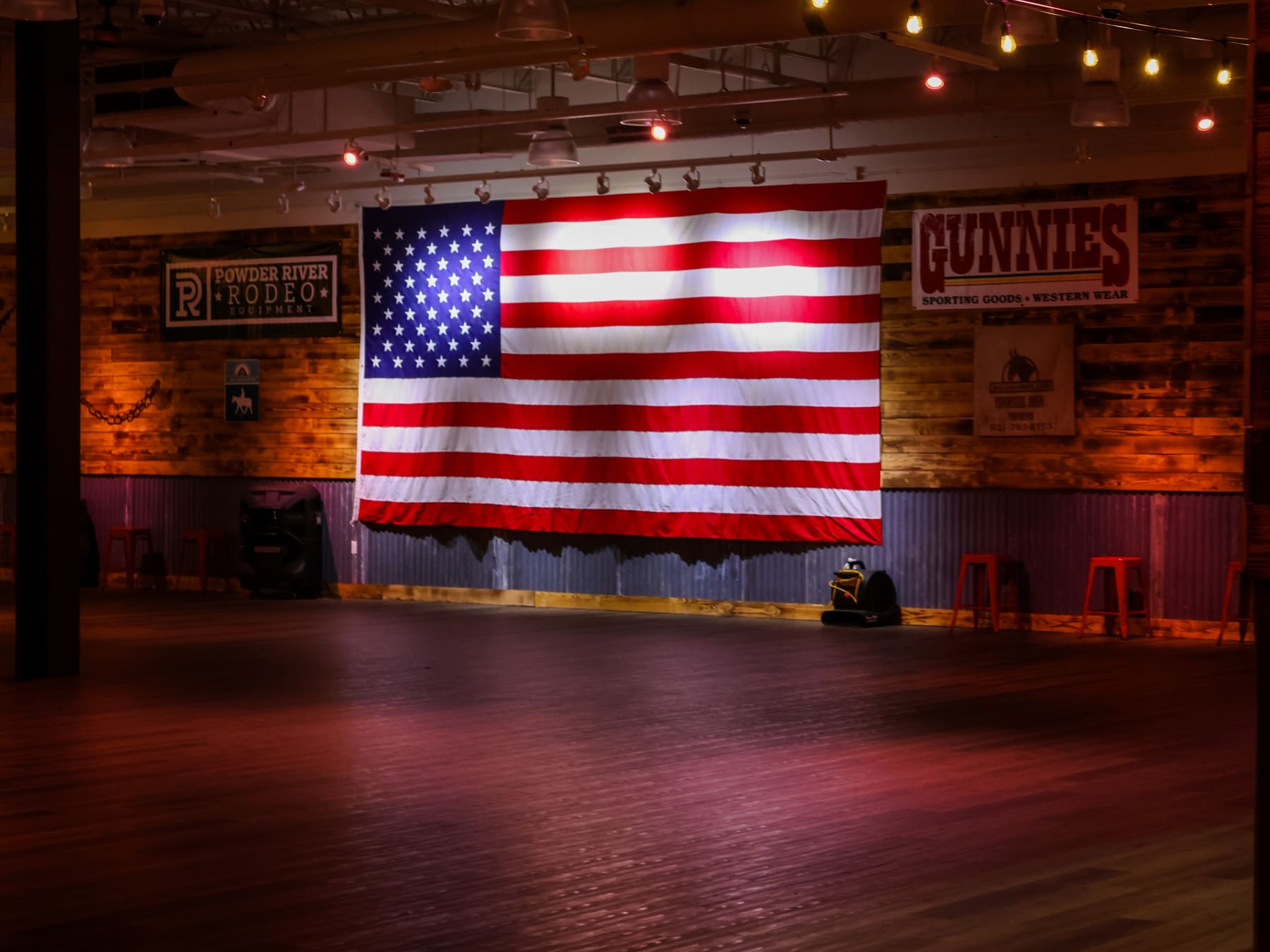 Large American flag lit above the empty hardwood dance floor