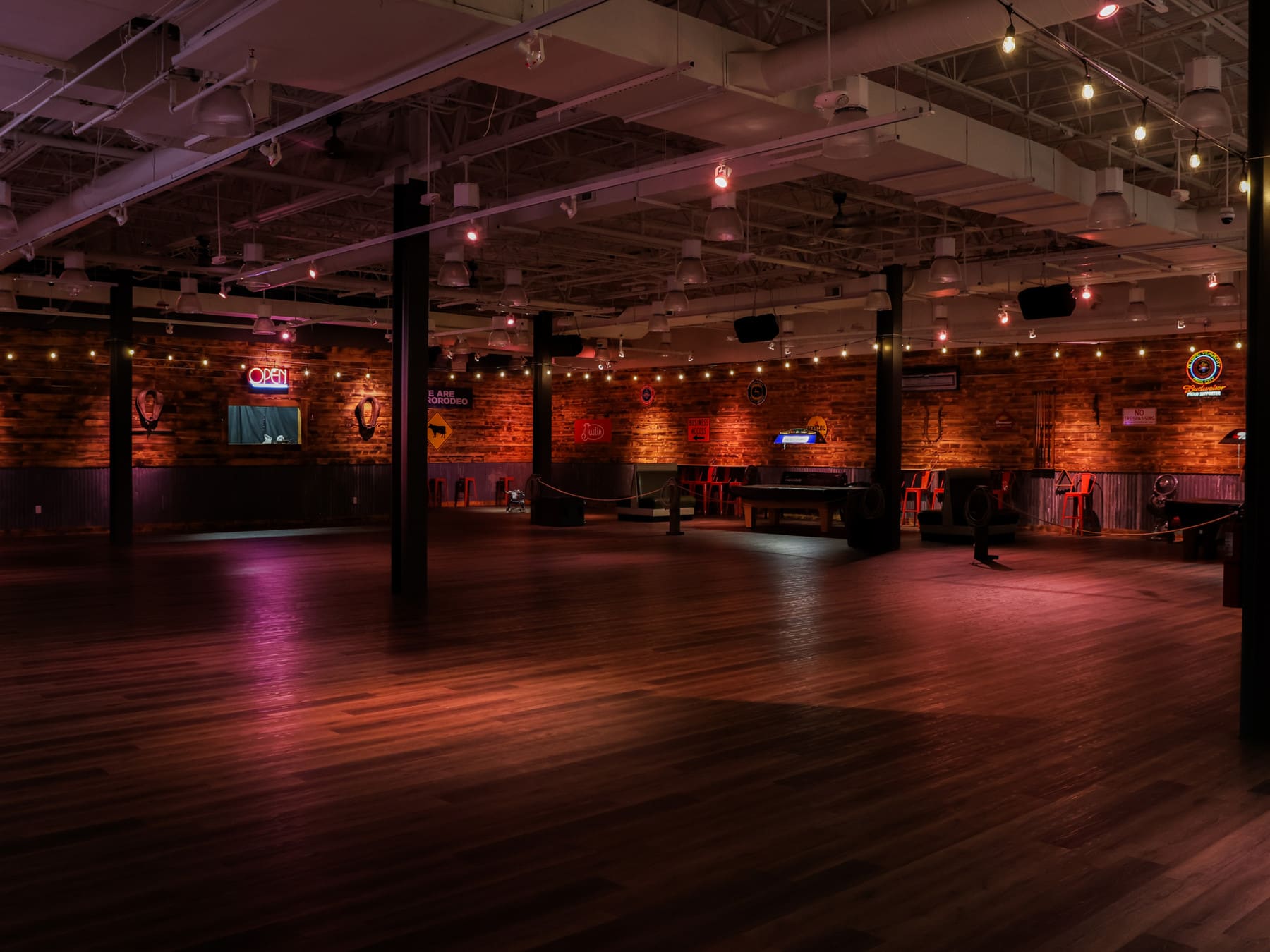 Wide view of Western Events Center hall with string lights and neon signs